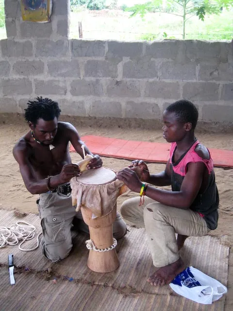 Kifimbo and Titus making a traditional drum from goat skin