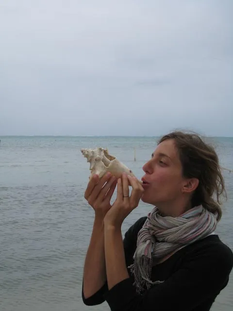 Robyn blowing a conch shell in Caye Caulker, Belize